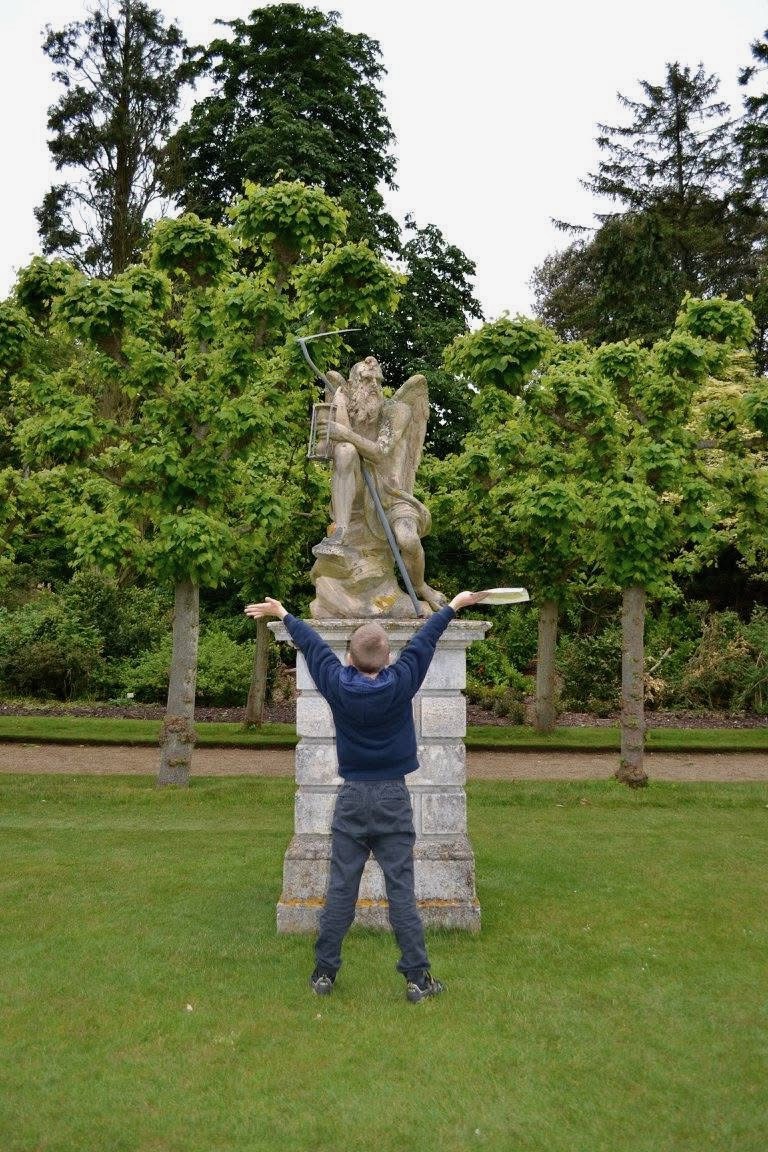 Harrison standing facing a statue of Father Time in Sandringham House Gardens.