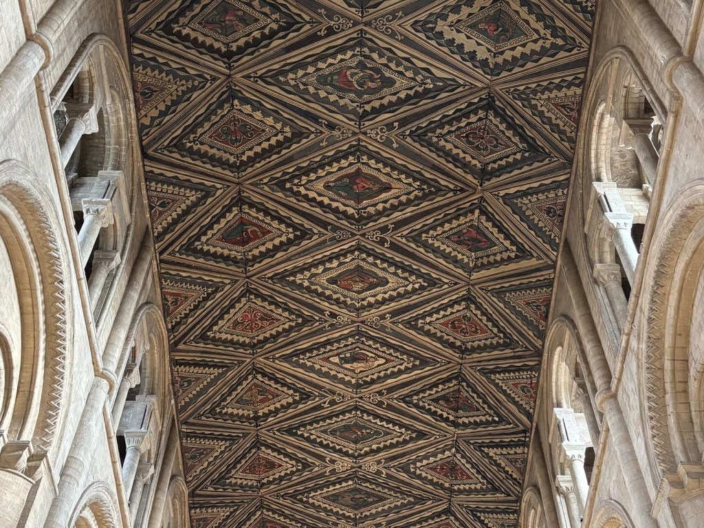 Wooden cathedral ceiling with layered diamond pattern.