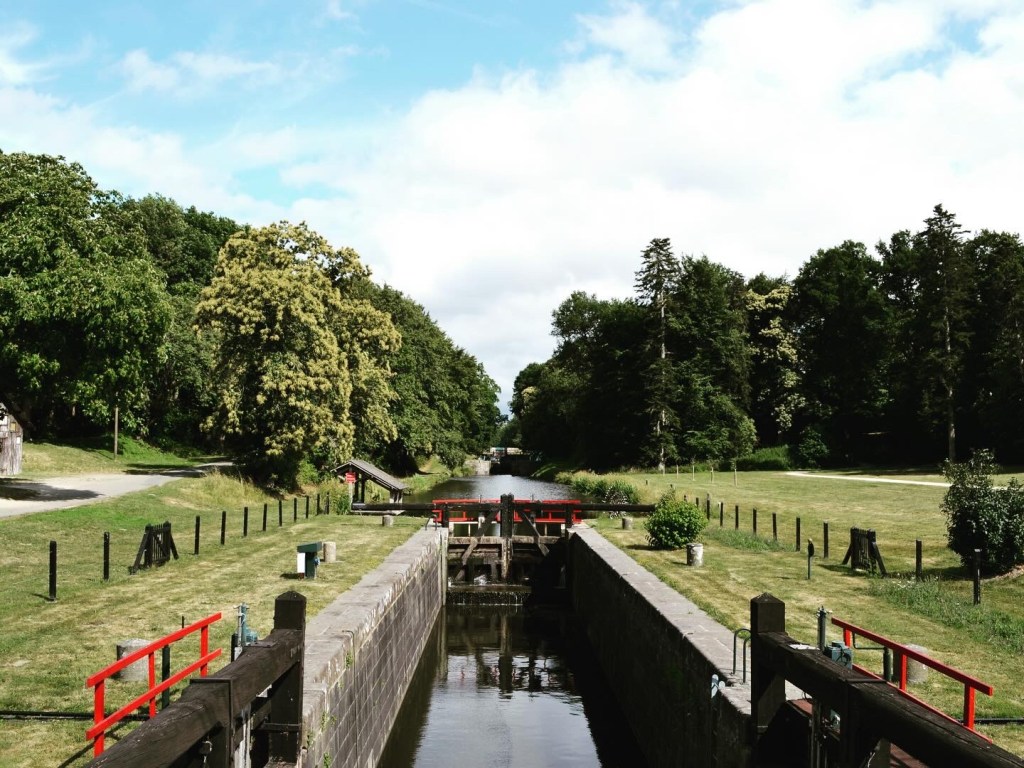 View up a canal with a closed lock holding back the water behind it.