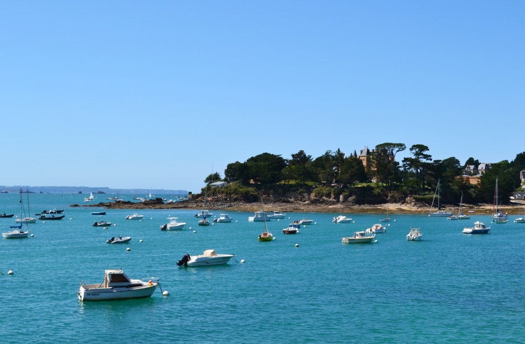 View of a harbour with small boats and a headland with trees behind it.