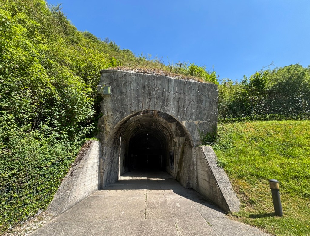 Entrance to concrete tunnel set into hillside.
